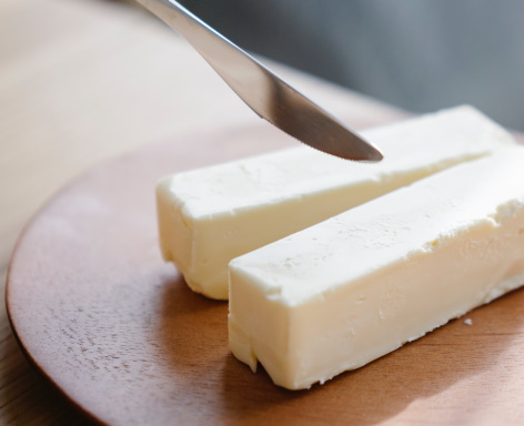 Sticks of butter with a butter knife above them.