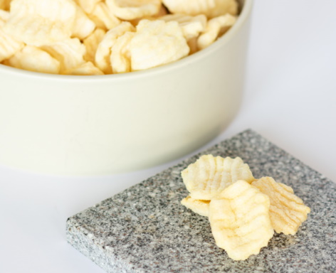 Curls of butter in a bowl with a few on a granite piece